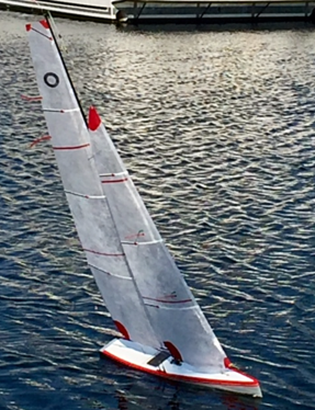 A sailboat is in the water and has red stripes on it.