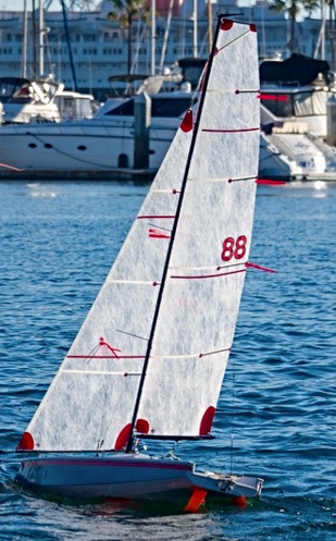 A sailboat is in the water near some boats.