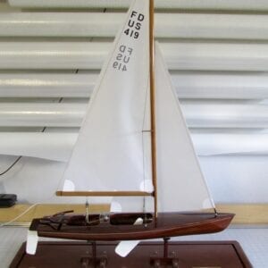 A small wooden boat with sails on the water.