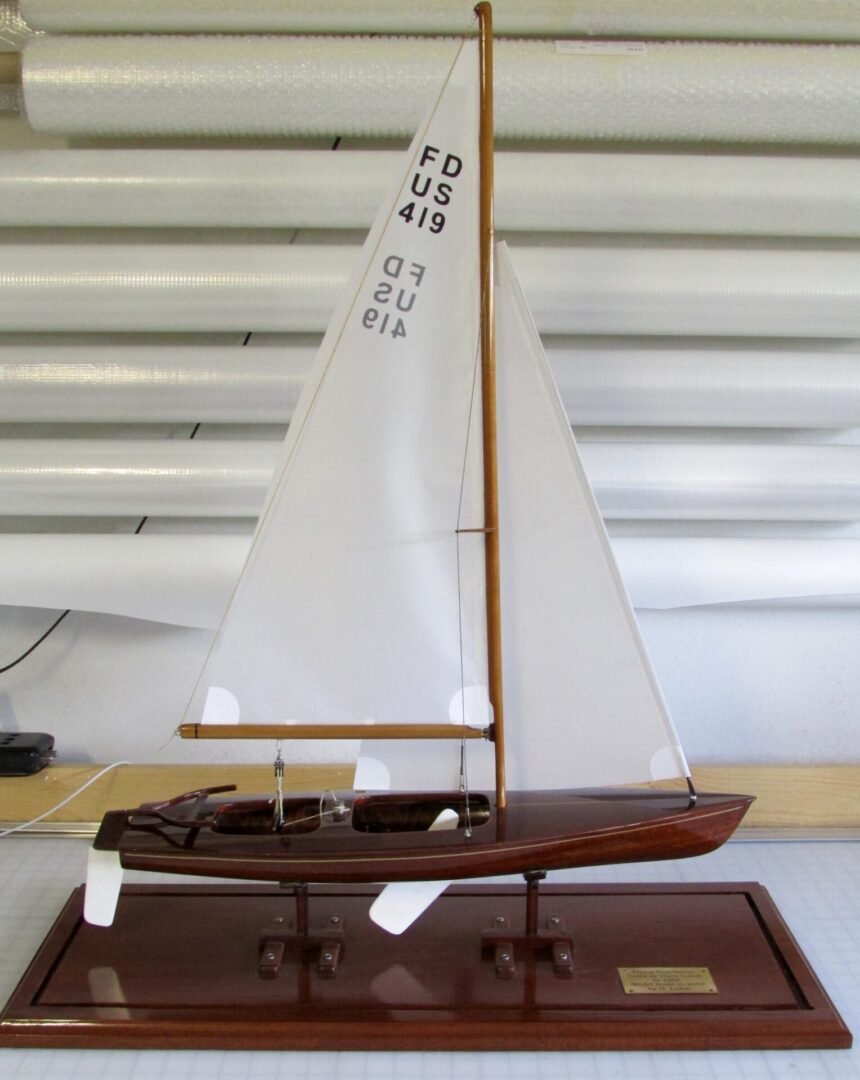 A small wooden boat with sails on the water.